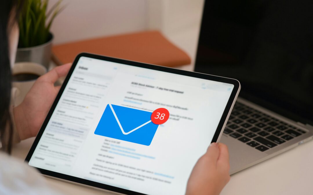 Hand holding an ipad which shows a full email inbox, with 38 new messages arriving