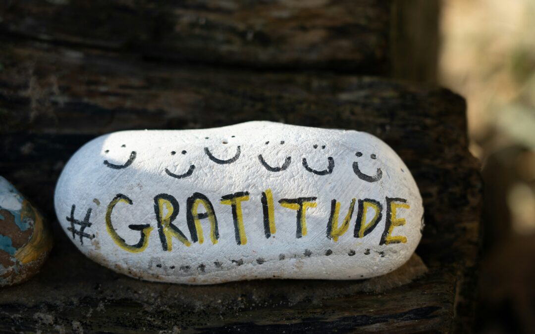A colorfully painted rock with the word "gratitude" to show how a gratitude practice can boost your happiness and productivity.
